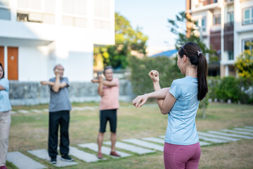 Group of elderly people exercising together with trainer in the garden.
