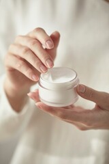 a woman holding cosmetics by a window in the sun