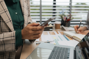 a businesswoman is using an electronic device to search and send information to her team, the marketing team leader is reviewing documents related to marketing data