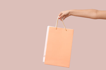 Female hand with paper shopping bags on light background. Valentine's Day celebration