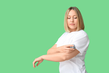 Woman with glucose sensor for measuring blood sugar level and applicator on green background....