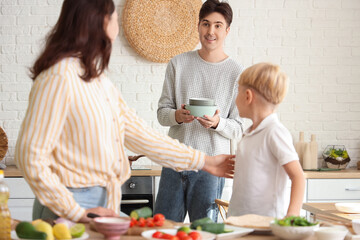 Young man with his wife and little son cooking Fajita in kitchen