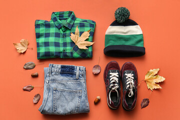 Composition with stylish children's clothes, shoes and fallen leaves on color background