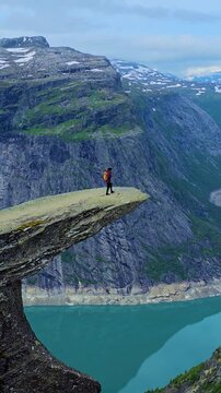 A lone adventurer stands atop a striking cliff edge, surrounded by breathtaking landscapes of Trolltunga Norway.