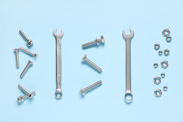 Tap bolts, chrome nuts and wrenches on blue background