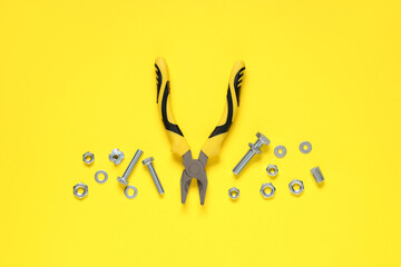 Tap bolts, chrome nuts and pliers on yellow background