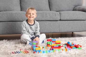 Happy cute little boy playing with colorful toy bricks on carpet at home