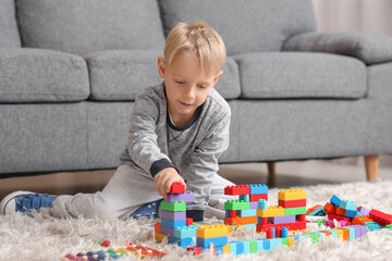 Cute little boy playing with colorful toy bricks on carpet at home