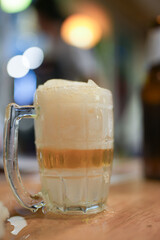 Frozen beer mug with foam on table and bokeh background