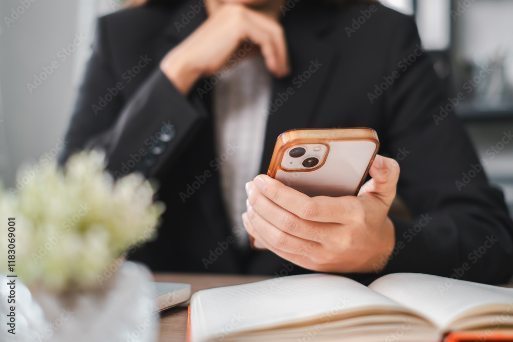 Poster a business professional in a suit using a smartphone at a desk with an open notebook and a small pla