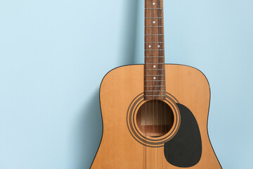 Obraz premium Acoustic guitar near color wall, closeup