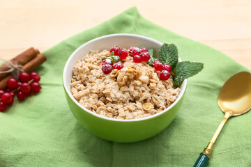 Bowl with tasty oatmeal and cranberries on wooden background, closeup