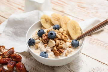 Napkin, bowl with tasty oatmeal, berries and nuts on white wooden background