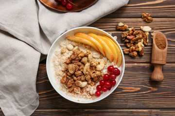 Composition with tasty oatmeal, pieces of apple, berries and nuts on wooden background