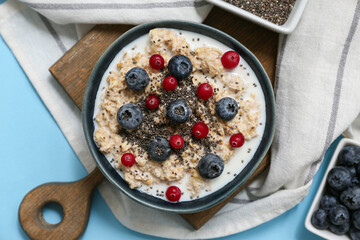 Composition with napkin, tasty oatmeal and berries on blue background, closeup