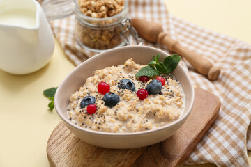 Composition with napkin, tasty oatmeal and berries on beige background
