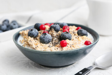 Bowl with tasty oatmeal, chia seeds and berries on white background, closeup