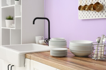 Clean plates and bowls near sink in stylish kitchen, closeup