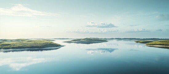 Obraz premium Serene landscape of tranquil lake with small islands under a peaceful sky.