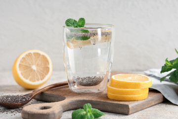 Glass of lemon water with chia seeds and mint on white grunge table, closeup
