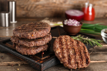 Tray with tasty meat cutlets on wooden background