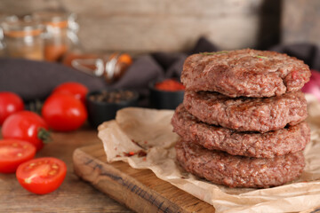Board with stack of tasty meat cutlets and tomatoes on wooden background