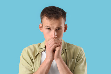 Apologizing young man on blue background, closeup