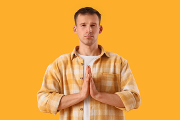 Apologizing young man on orange background