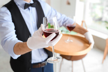 Male waiter holding tray with glasses of wine in restaurant, closeup