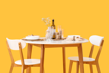 Served restaurant table with flowers on yellow background