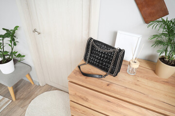 Black bag with reed diffuser and frame on commode in hallway