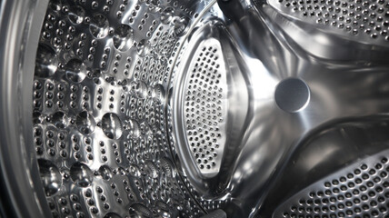 Inside of washing machine. Rotating inner tub. Material metal. Close up of electrical household appliance.