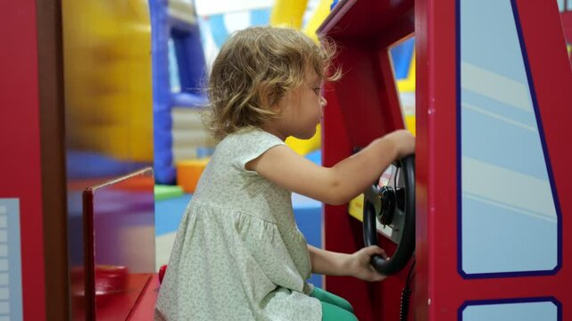 Cute toddler girl playing with toy steering wheel in play area