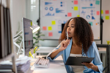 A woman is sitting at a desk with a computer monitor in front of her