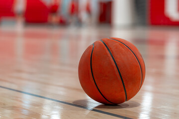 Close up photo of a basketball on a new hardwood gym, court, floor with a blurry background.
