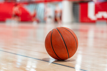 Close up photo of a basketball on a new hardwood gym, court, floor with a blurry background.
