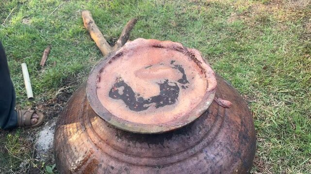 Removing excess foam from pot during areca nut boiling process. Handheld, high angle