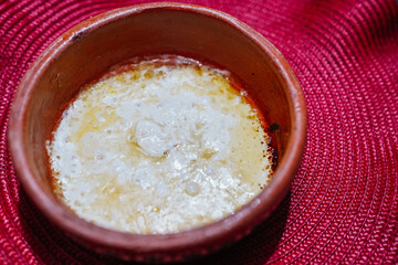 Melting butter in terracotta bowl for grilled cheese on red placemat