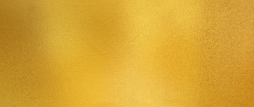 Gold wall texture background. Yellow shiny gold foil paint on wall surface with light reflection, vibrant golden luxury wallpaper