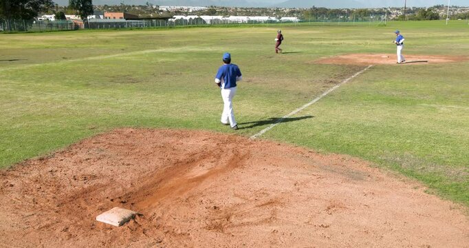 Playing baseball, pitcher throwing ball while batter running to first base