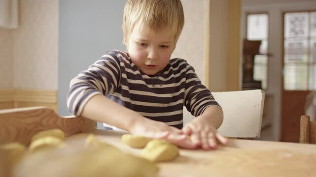 Boy in kitchen rolling dough to bake traditional Swedish Christmas saffron buns