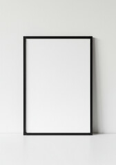 Fototapeta premium Black frame leaning against white wall, perfect for interior design inspiration