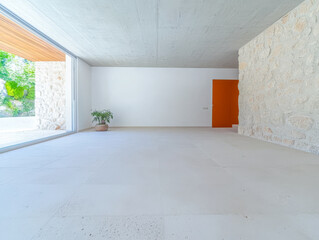 Modern minimalist interior with stone wall and vibrant orange door in bright daylight