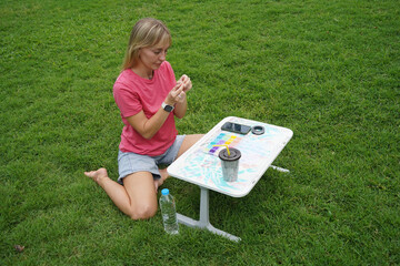 Young woman beading colorful bracelets outdoors in a park