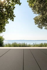 Fototapeta premium Scenic waterfront view with clear blue sky and lush greenery in the foreground at midday