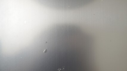 Polished metal surface with faint, opaque marks, creating a contrast between shiny and matte sections, giving it a weathered, yet elegant look.
