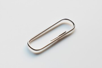 Metallic paperclip placed on clean white surface
