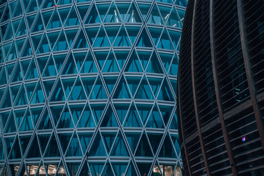 Geometric Facade: A close-up shot of a modern glass and steel skyscraper with a mesmerizing geometric pattern of triangles. The intricate design, reminiscent of a tessellated artwork.
