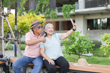 Fototapeta premium Asian senior couple traveler enjoying trip and vacation in downtown, Senior travel couple takes a selfie