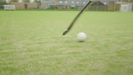 Field hockey player pushing ball with the stick on the artificial grass play field - Slow motion - Powered by Adobe